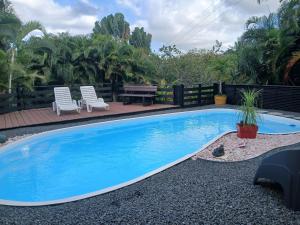 a blue swimming pool with two chairs and a table at Gwadakaz in Sainte-Rose