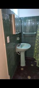 een groene betegelde badkamer met een wastafel en een douche bij PH en Mar de Ajó Centro in Mar de Ajó