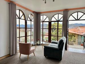 a living room with large windows and a couch and chair at Casa Encuentro San Blas in Cusco