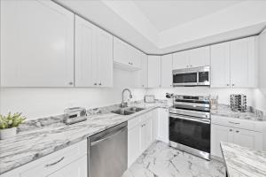 uma cozinha branca com bancadas em mármore e electrodomésticos em RIVER FLY IN Coastal Penthouse Panoramic Views RFI-708 em Audubon mais 63 fotografias