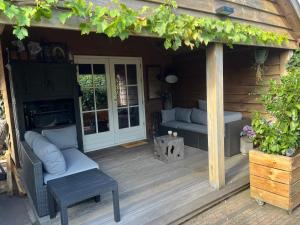 a porch of a wooden house with a couch and chairs at Het Houten Huis in Hierden