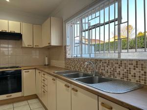 eine Küche mit Spüle und Fenster in der Unterkunft Monkoma Apartments in Mbabane