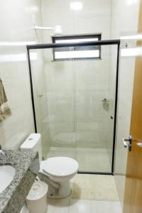 a bathroom with a toilet and a glass shower at Ap7 - Studio Completo a Minutos das Compras no Paraguai in Guaíra