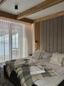 ein großes Bett in einem Zimmer mit einem großen Fenster in der Unterkunft GreenHill Bachleda in Zakopane