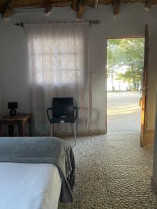 una camera con un letto e una sedia di fronte a una finestra di Edsam Lodge a Divundu