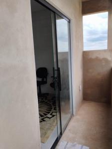 een glazen schuifdeur met een stoel in een kamer bij Suíte 4 Centro de São Thomé das Letras in São Thomé das Letras