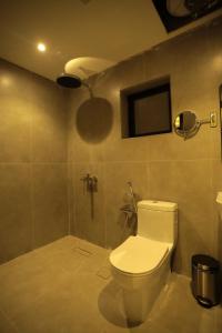 Un baño con inodoro y un televisor en la pared. en منازل الحساء للشقق الفندقية, en Al Hofuf