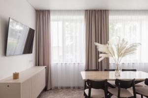 een eetkamer met een tafel met stoelen en een vaas met bloemen bij Varenastay in Varėna