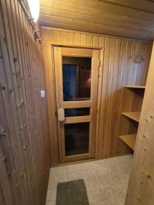 a small room with wooden walls and a glass door at Gyékény Pihenő in Szarvas