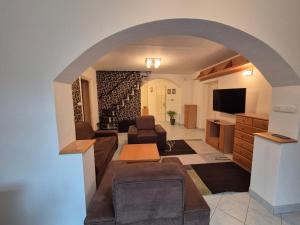 a living room with an archway with a couch and a tv at Gyékény Pihenő in Szarvas
