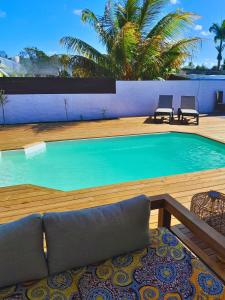 a swimming pool with two chairs and a palm tree at Villa La Kaz a Gwada in Port-Louis