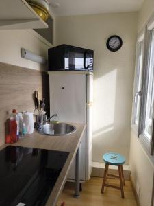 eine Küche mit einer Spüle und einer Mikrowelle über einem Kühlschrank in der Unterkunft T2 PLEIN CENTRE - 100m marché LA BAULE in La Baule