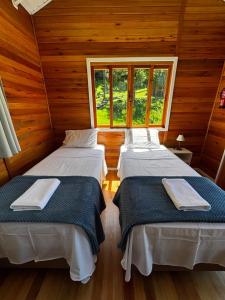 2 letti in una camera con pareti e finestre in legno di Quinta Terra Sagrada a Urubici