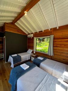 due letti in una stanza con finestra di Quinta Terra Sagrada a Urubici Altre 62 foto