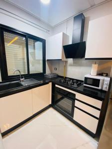 een keuken met zwart-witte kasten en een magnetron bij Dar awina in Bin Rhilouf