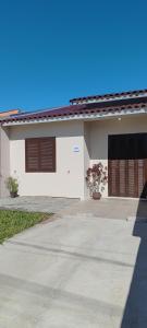 a white house with brown doors and a driveway at Casa de Benê in Tramandaí