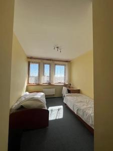 een slaapkamer met twee bedden en een raam bij Hotel Sowa in Częstochowa