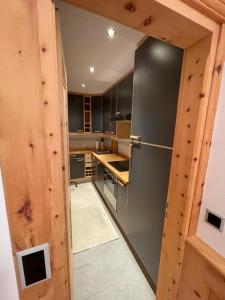 a kitchen with a stainless steel refrigerator and wooden walls at 2,5 Zimmer Wohnung mit Bergblick in Engadin in Zuoz