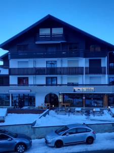 zwei Autos auf einem Parkplatz vor einem Gebäude geparkt in der Unterkunft Le Panoramic in Thollon