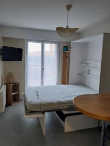 a bedroom with a bed with a table and a window at Chez Fany et Ben in Cabourg
