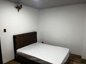 um pequeno quarto com uma cama com lençóis brancos em la terraza em Armenia