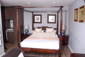 een slaapkamer met een hemelbed met witte lakens bij Nautilus Guesthouse in Port Elizabeth