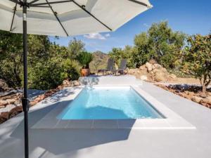an outdoor swimming pool with an umbrella and chairs at 5-Bedroom Villa with Pool, Swimjet and Jacuzzi in Comares