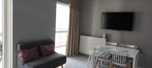 a living room with a chair and a table and a television at Parastaseis City Apartment Central in Patra