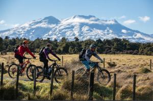 three people riding bikes in a field with mountains in the background at Funski Lodge sleeps 10 Where Adventure Begins in Taumarunui