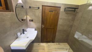 a bathroom with a sink and a wooden door at WILD PARADISE Apt in Unawatuna +29 photos