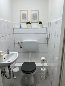 ein weißes Badezimmer mit einem schwarzen WC und einem Waschbecken in der Unterkunft HouseofGeneration am Marienplatz in Stuttgart