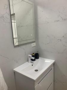 a white bathroom with a sink and a mirror at Будинок з чаном in Druzhba