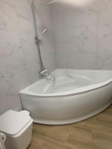 a white bath tub in a bathroom with a toilet at Будинок з чаном in Druzhba