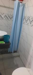 Un baño con una cortina de ducha azul al lado de un inodoro. en Ponta Family holiday house, en Ponta do Ouro 16 fotos más