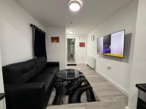 ベッドフォードにあるCosy Six Bedroom house in Bedford Townの黒いソファとテーブルのあるリビングルーム