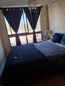 um quarto com uma cama grande e uma janela grande em Amplio departamento viña centro em Viña del Mar