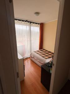 um pequeno quarto com uma cama e uma janela em Amplio departamento viña centro em Viña del Mar