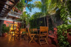 un patio con mesa, sillas y palmeras en Hotel 3 Banderas en Cartagena de Indias