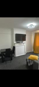 een woonkamer met een tv en een tafel en stoelen bij Grove manor in Streatham Vale