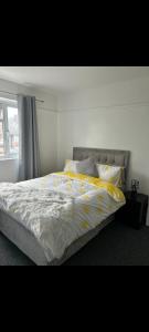 een bed met gele en witte lakens en een raam bij Grove manor in Streatham Vale +11 foto's