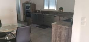 CapesterreにあるVilla de charmesのガラスのテーブル、テーブル、椅子付きのキッチン