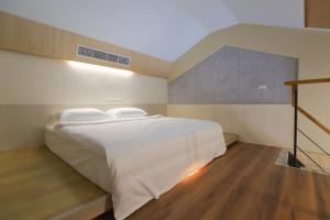 Un dormitorio con una gran cama blanca y una escalera. en 光隅民宿 Light Haus Inn, en Hengchun