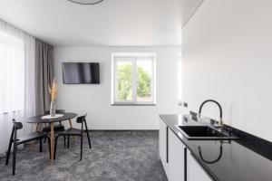 a white kitchen with a table and a sink at Varenastay in Varėna