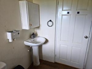 a bathroom with a white sink and a door at Cozy Hill Vista in Micoud +27 photos