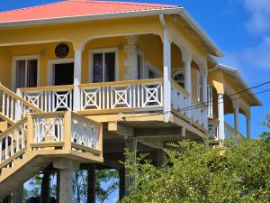 a yellow house with a balcony on top of it at Cozy Hill Vista in Micoud
