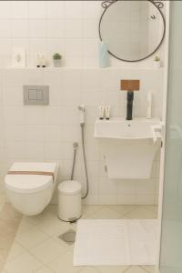 een witte badkamer met een toilet en een wastafel bij Liora Inside Al Dana beach Resort in Half Moon Bay
