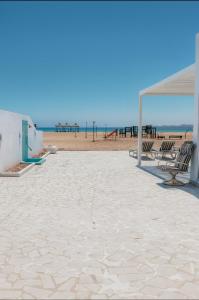 een zandstrand met stoelen en een prieel bij Liora Inside Al Dana beach Resort in Half Moon Bay