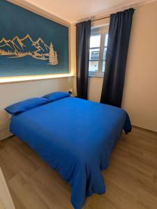 Il Boschetto della Valle Maira في Villar San Costanzo: سرير أزرق في غرفة نوم مع نافذة