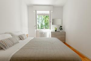 Un dormitorio blanco con una cama grande y una ventana. en Milan - Refuge in the Green, en Cusano Milanino