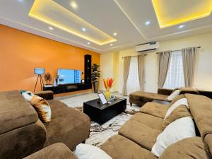 a living room with two couches and a flat screen tv at StayatMargarets in Abuja